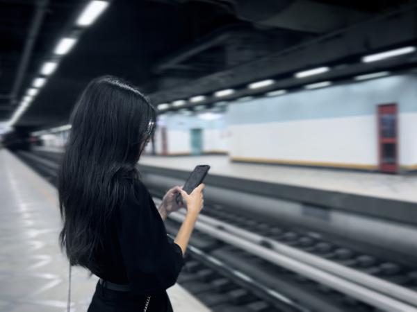 Female using her mobile on a Metro platform subway